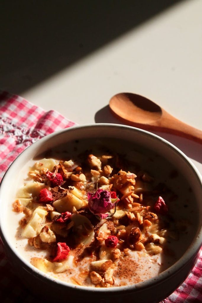 A delightful breakfast bowl filled with yogurt, granola, nuts, and fruits on a checkered cloth.